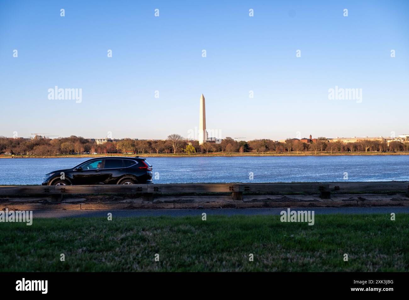 Monumento a Washington dal Lady Bird Johnson Park Washington DC | WASHINGTON DC — Il Monumento a Washington è visto dal Lady Bird Johnson Park, con il fiume Potomac e le auto sulla George Washington Parkway in primo piano. Il parco, intitolato all'ex First Lady, offre viste panoramiche sull'iconico obelisco e sul paesaggio circostante. Il monumento, alto 555 piedi, serve come tributo al primo presidente della nazione, George Washington. Foto Stock