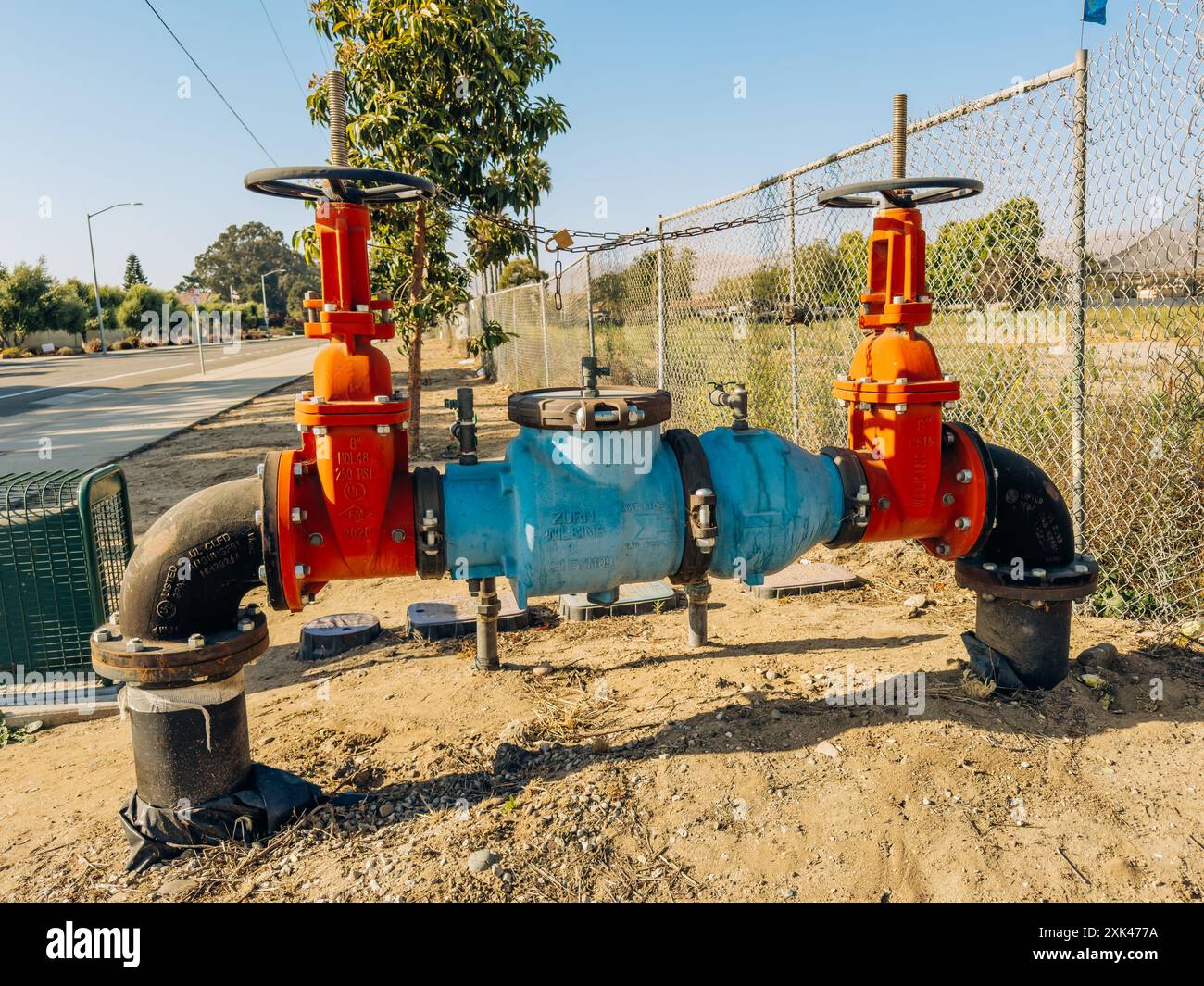Santa Maria, California, USA - 20 luglio 2024. Sistema di valvole dell'acqua industriali di grandi dimensioni con manici arancioni e tubi blu. Foto Stock