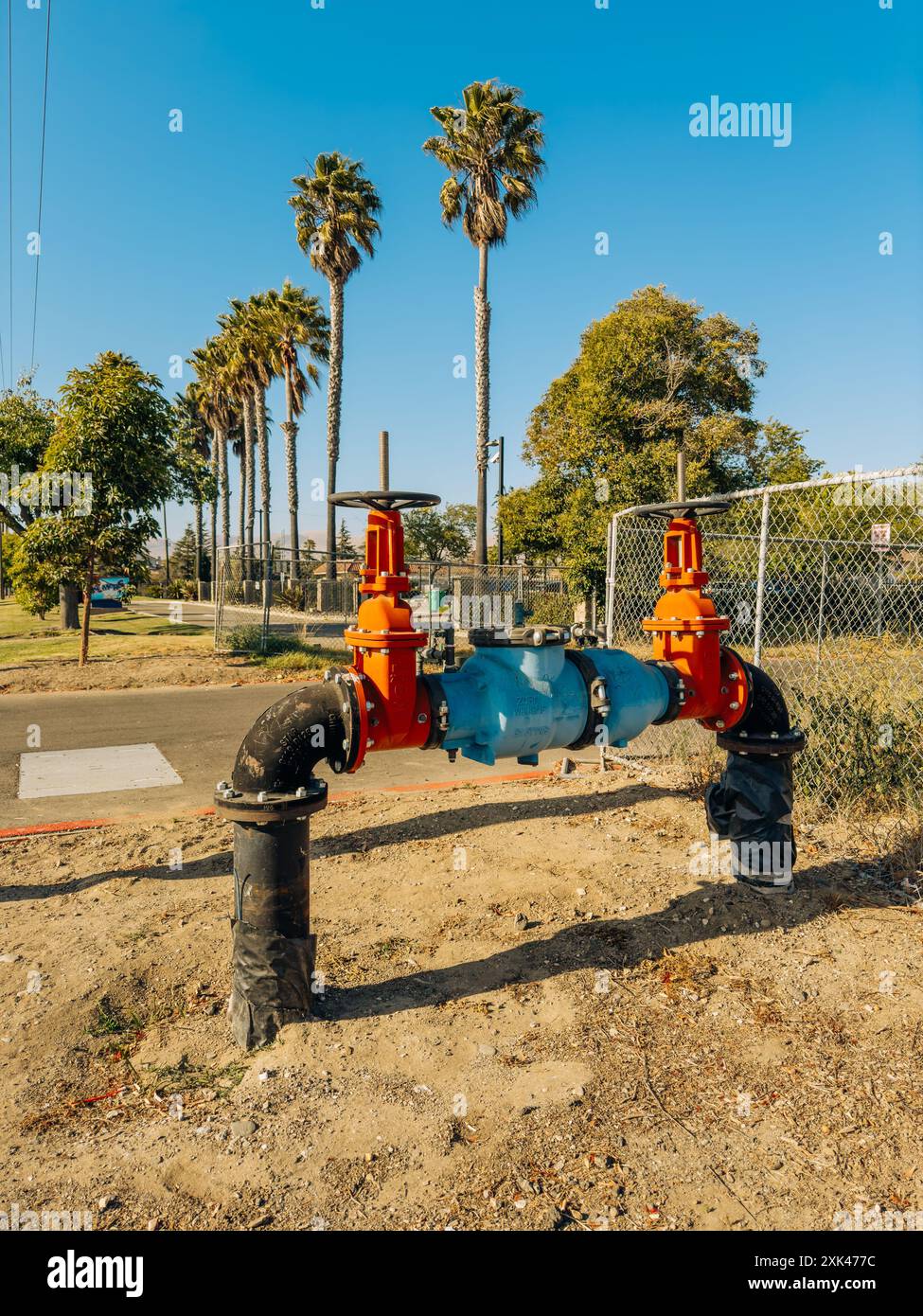 Santa Maria, California, USA - 20 luglio 2024. Sistema di valvole dell'acqua industriali di grandi dimensioni con manici arancioni e tubi blu. Foto Stock