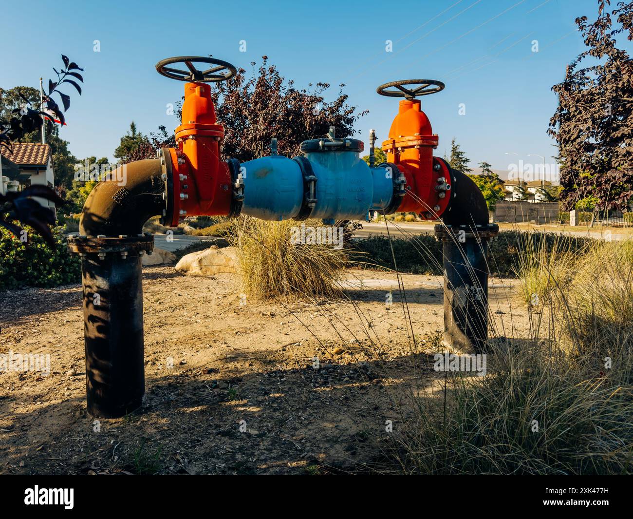 Santa Maria, California, USA - 20 luglio 2024. Sistema di valvole dell'acqua industriali di grandi dimensioni con manici arancioni e tubi blu. Foto Stock