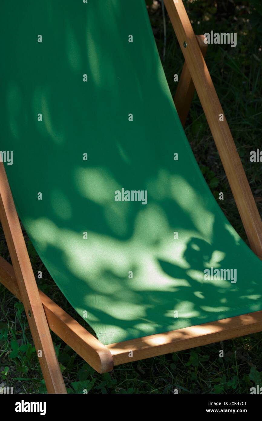 Luce del sole su una sdraio verde vuota all'ombra Foto Stock