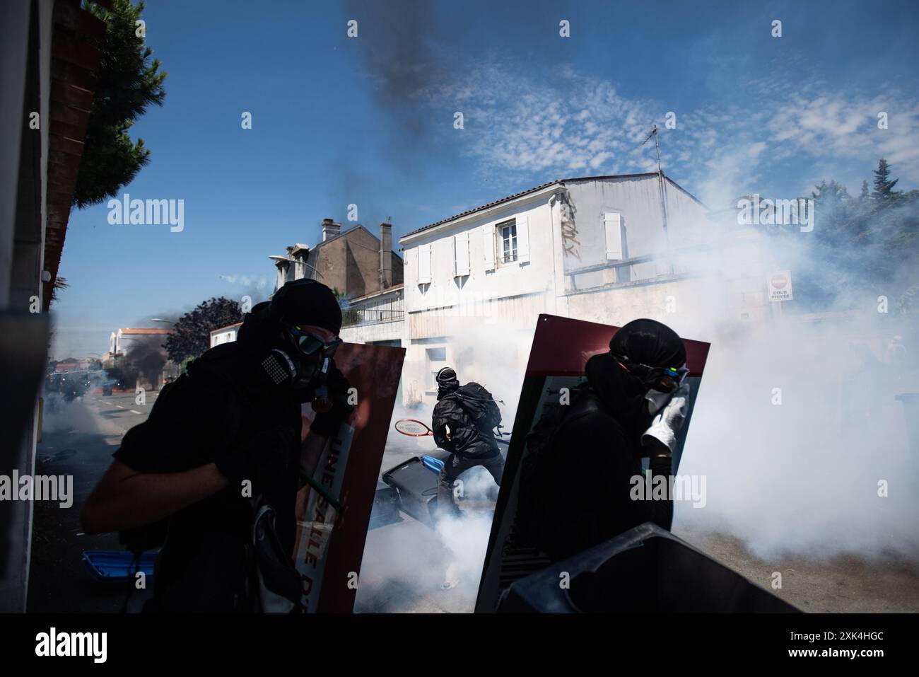 La Rochelle, Francia. 20 luglio 2024, la Rochelle, Francia: Un manifestante con una racchetta da tennis attende di colpire i pellet di gas lacrimogeni sparati dalla polizia, mentre altri due prendono il riparo dietro scudi improvvisati. Crediti: Jay Kogler/Alamy Live News crediti: Jay Kogler/Alamy Live News Foto Stock