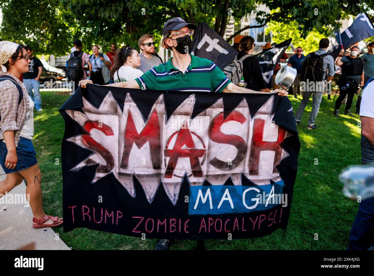 Milwaukee, Stati Uniti. 18 luglio 2024. Una persona detiene una bandiera che legge, "Smash MAGA, Trump Zombie Apocalypse", mentre i tester marciano e protestano contro la morte di due uomini neri, Samuel Sharpe Jr., per mano della polizia fuori città presso l'RNC, e D'Vontaye Mitchell, presumibilmente picchiato dai dipendenti dell'hotel, l'ultimo giorno della Convention Nazionale Repubblicana (RNC), a Milwaukee, Wisconsin. La convenzione proseguì come previsto nonostante il tentativo di assassinio contro Trump e si concluse con lui accettando la nomina presidenziale del suo partito. Credito: SOPA Images Limited/Alamy Live News Foto Stock