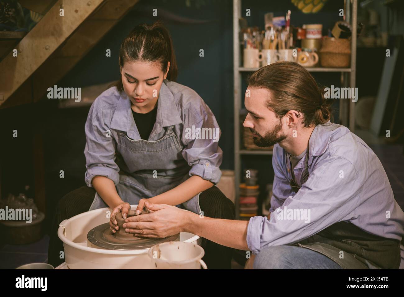 Uomo e donna mani che lavorano su una ruota di ceramica e fanno una pentola insieme coppia amante. Foto Stock