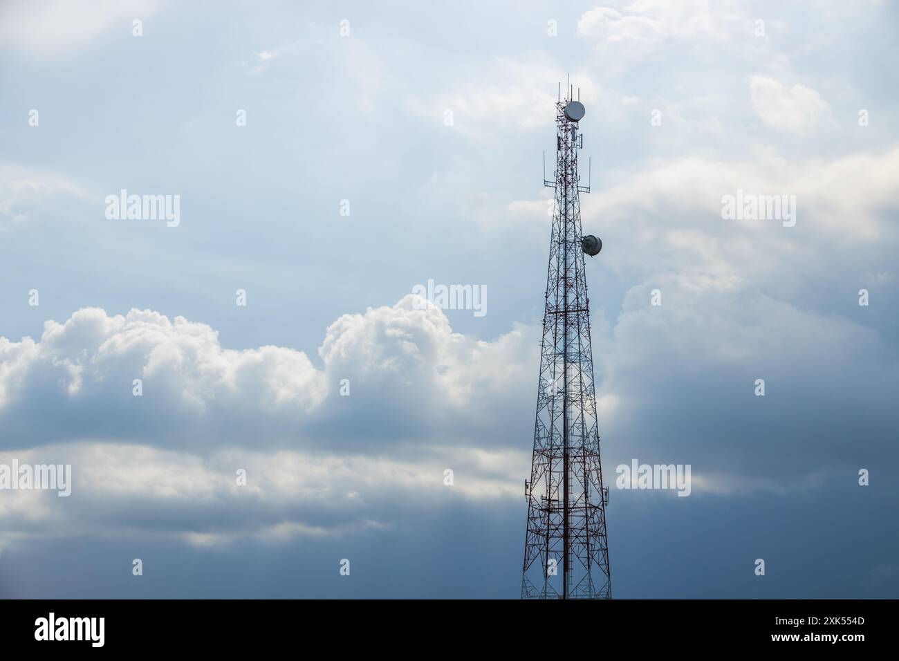 Torretta di segnalazione per telecomunicazioni 5G. Torre per telecomunicazioni su un cielo azzurro nuvoloso per lo sfondo, concetto di rete mobile tecnologica. Foto Stock