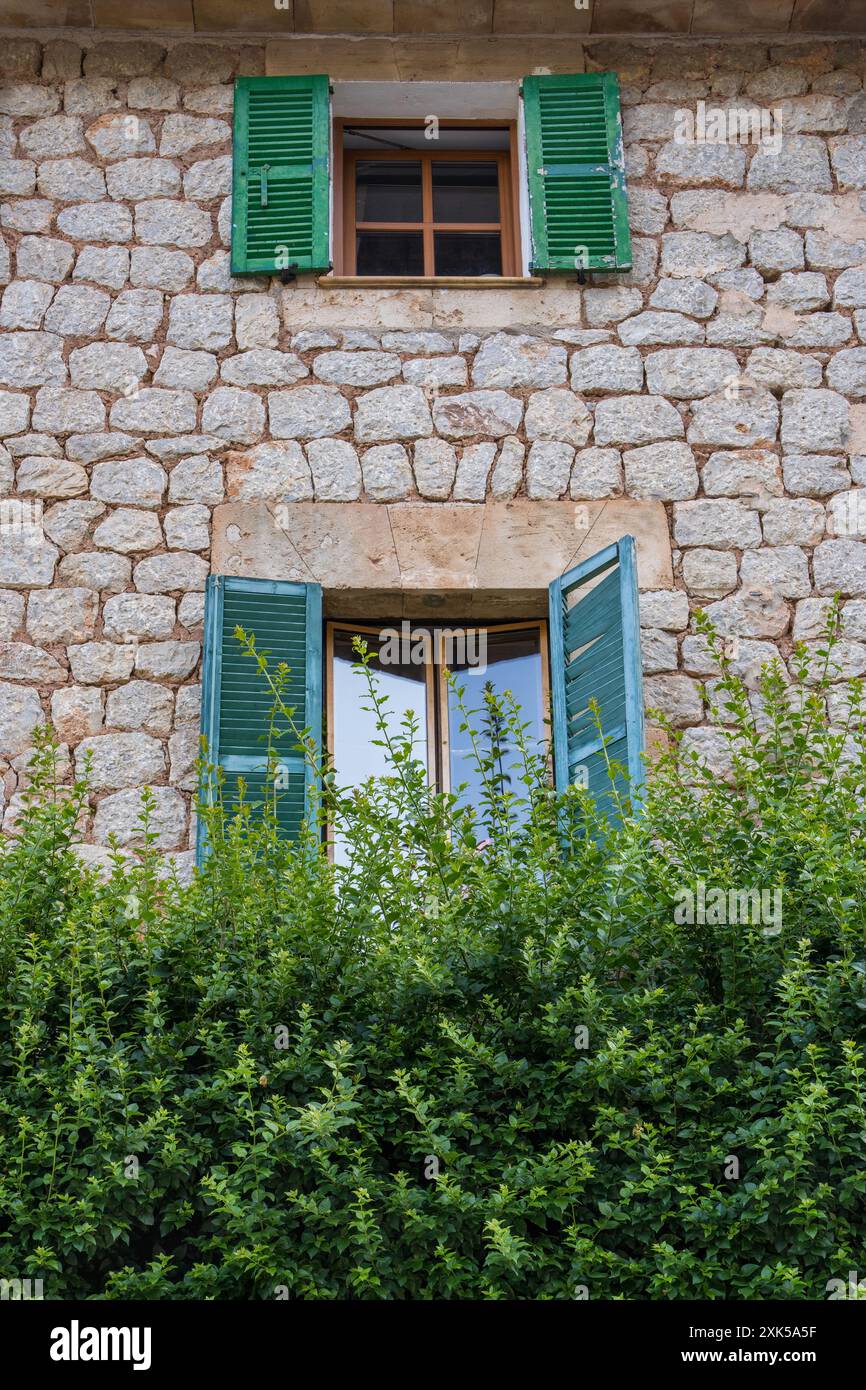 muro in pietra in una casa con finestra, persiane in legno verde. Port de Soller, Maiorca, Mar Mediterraneo, Spagna Foto Stock