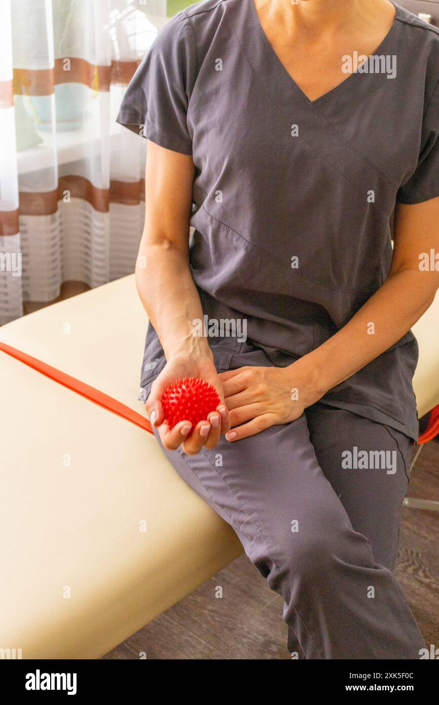 Shot della donna medico terapista manuale che tiene in mano la palla da massaggio portatile Foto Stock