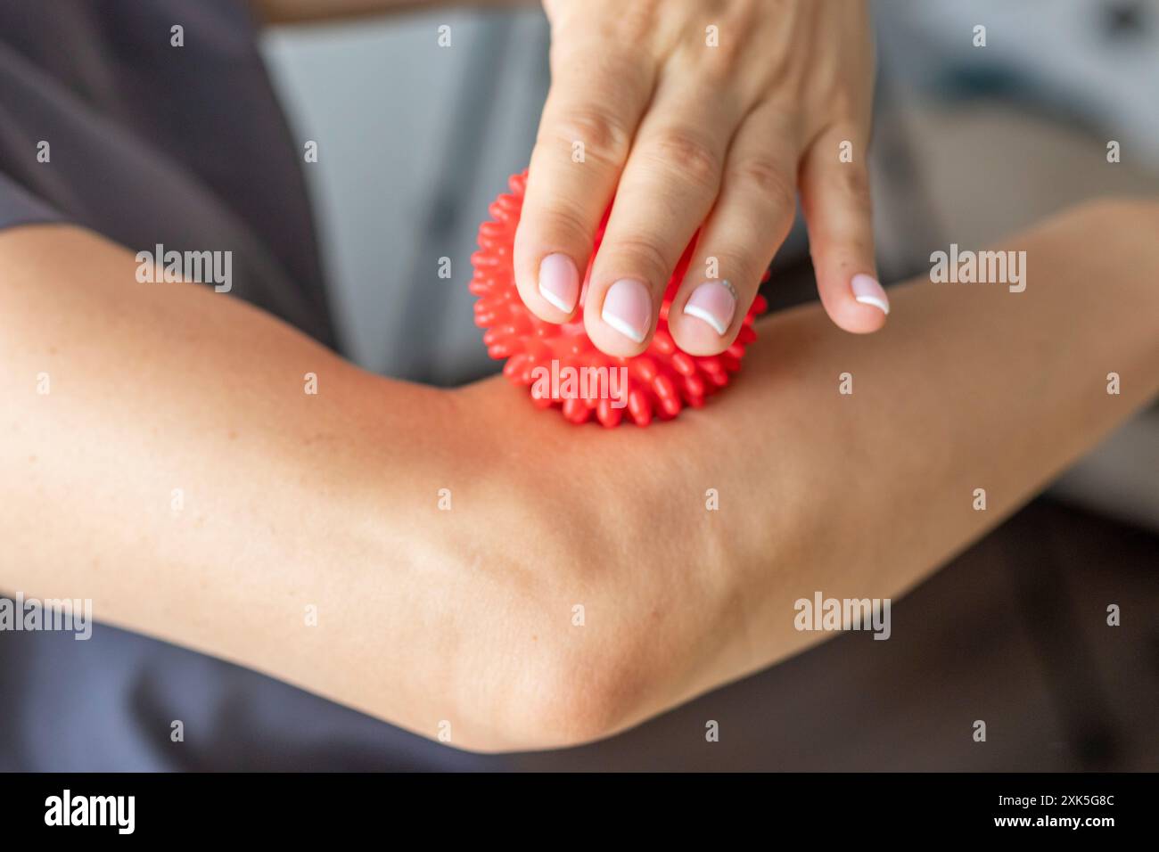 Shot della donna medico terapista manuale che tiene in mano la palla da massaggio portatile, mostrando come applicare pressione con essa Foto Stock