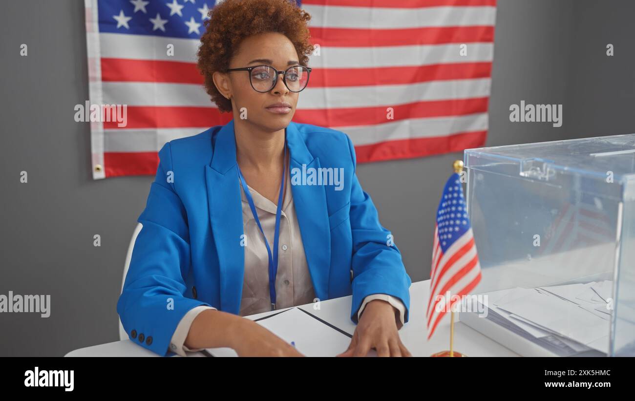 Donna afroamericana in un blazer in un collegio elettorale con voto e bandiera di noi Foto Stock