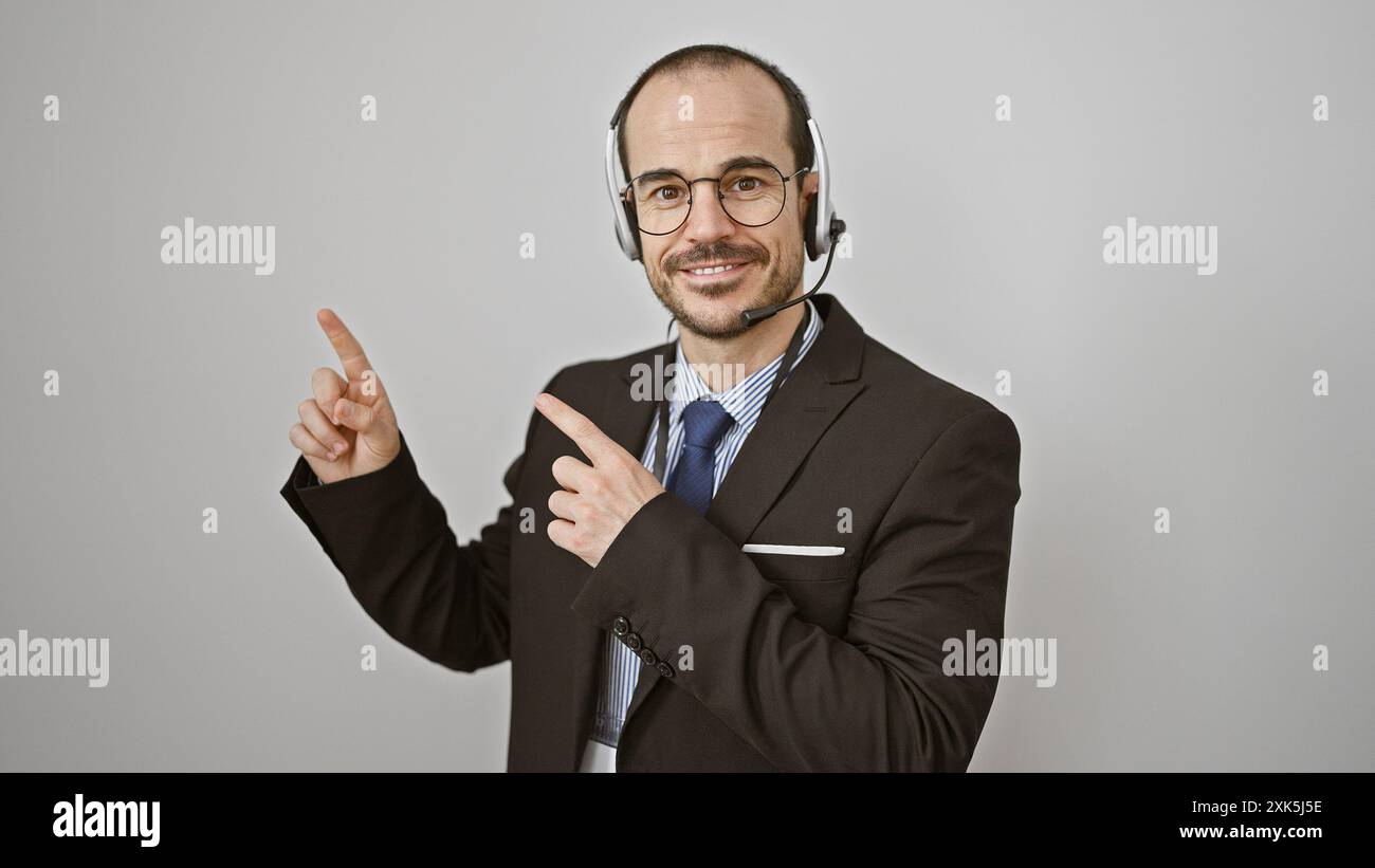Un uomo sorridente con la cuffia e la tuta si muove positivamente su uno sfondo bianco. Foto Stock