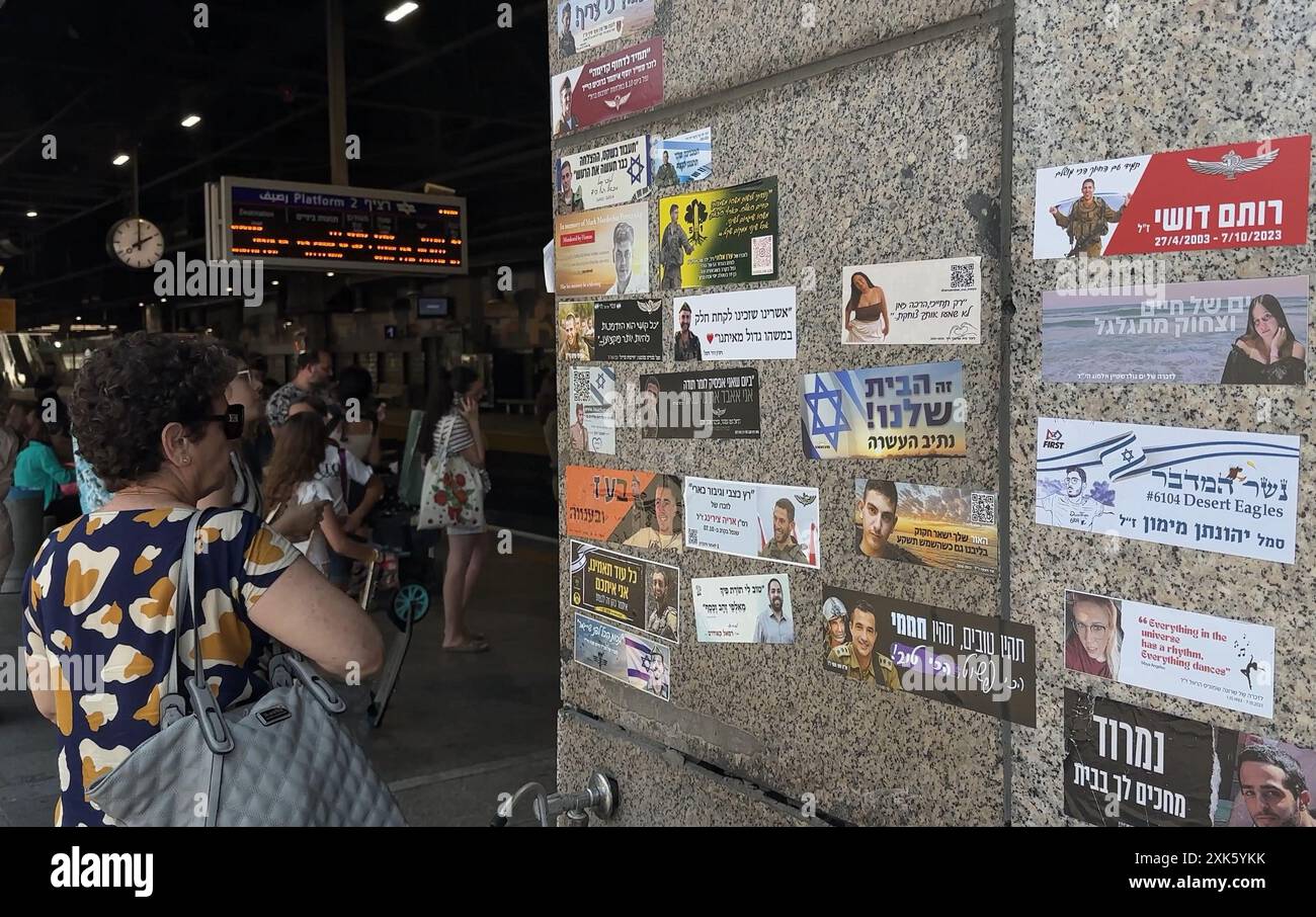 TEL AVIV, ISRAELE - 21 LUGLIO: i pendolari si trovano accanto a un muro con adesivi commemorativi che commemorano i soldati IDF uccisi nella guerra israeliana a Gaza e ter­ror vic­tims dopo Octo­ber 7, nella stazione ferroviaria hashalom, in mezzo alle continue battaglie tra Israele e il gruppo militante Hamas a Gaza il 21 luglio 2024 a Tel Aviv. Israele. Foto Stock