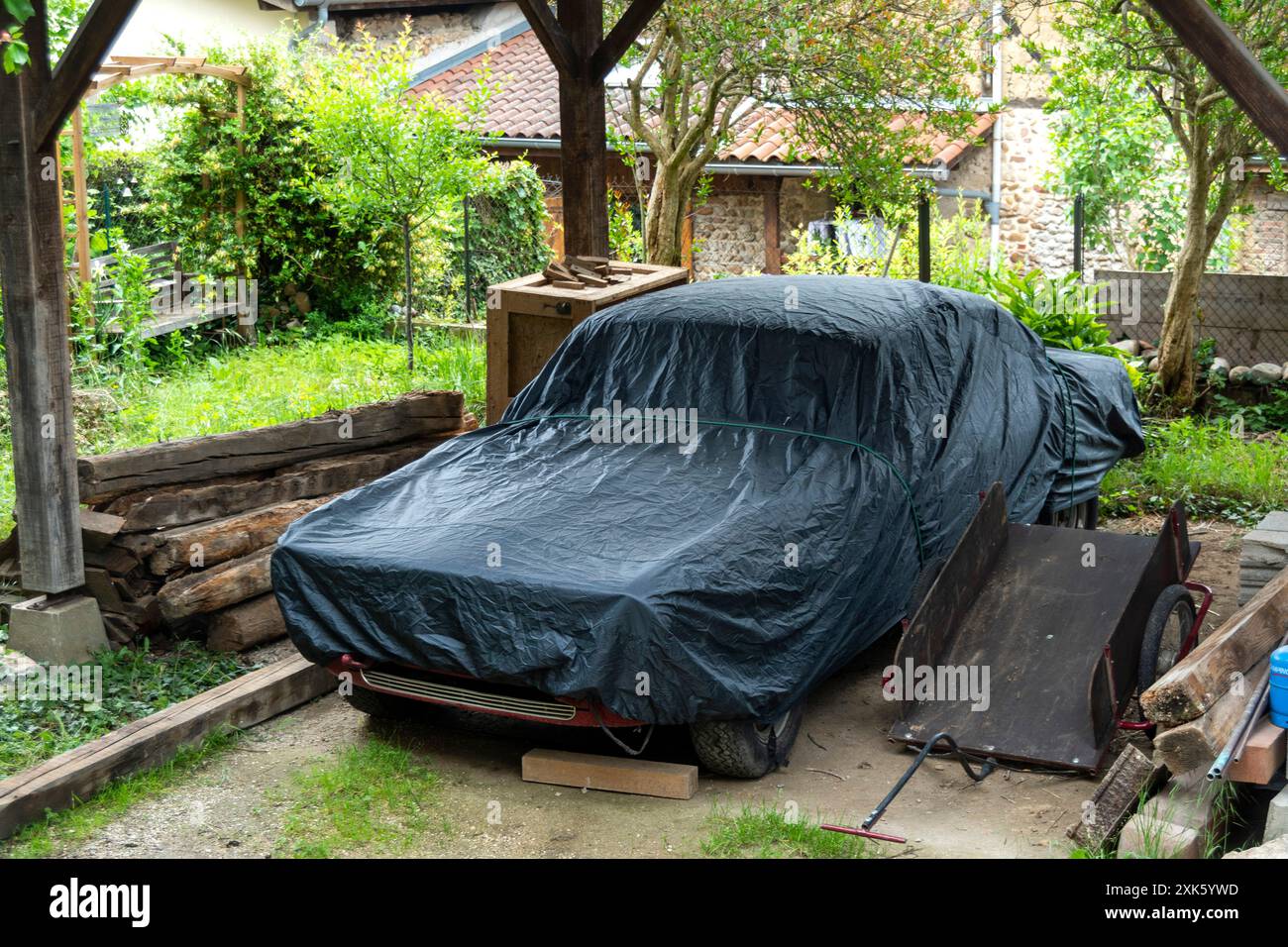Auto coperta parcheggiata sotto la Pergola di legno nel Giardino francese Foto Stock
