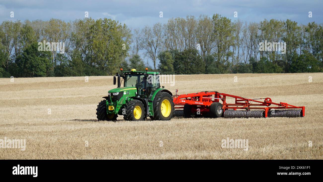 Trattore sul campo con impacchettamento del terreno King Roller nelle giornate di sole Foto Stock