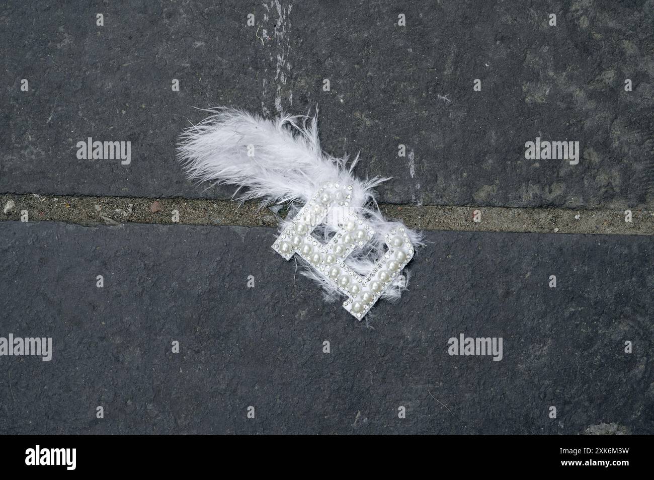 Lettera e con una piuma attaccata e caduta su un marciapiede Foto Stock