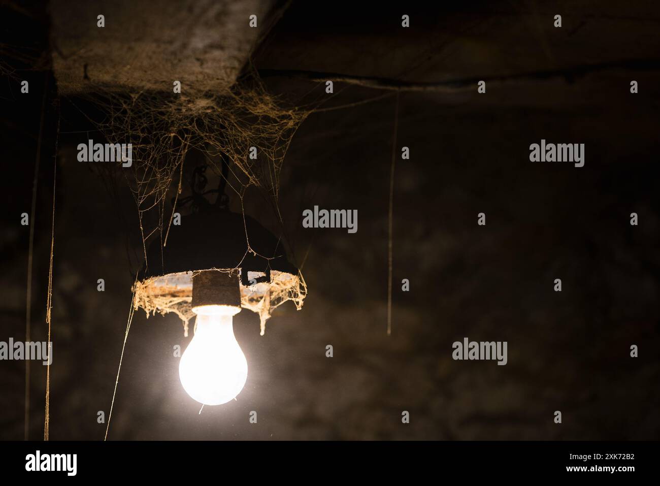 Lampada luminosa in un fienile sporco con vecchie ragnatele Foto Stock