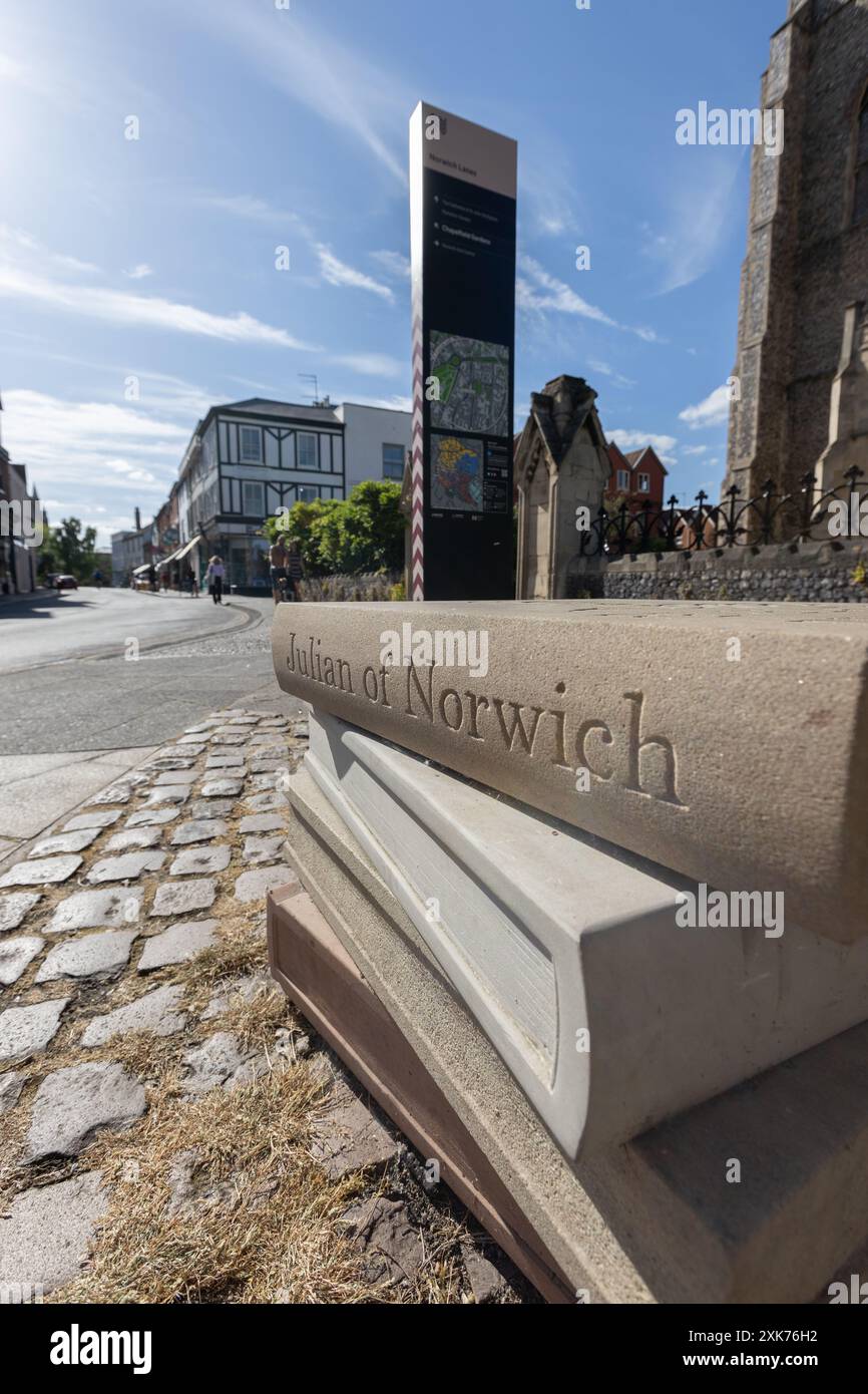 Un banco di lavoro in pietra di libri con il libro in alto che etichettava Julian of Norwich fuori St. Giles on the Hill Church a Norwich, Regno Unito, alla luce del giorno. Foto Stock