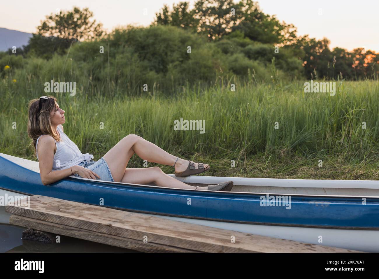 Ritratto di una giovane donna che si rilassa in canoa su un lago nella natura Foto Stock