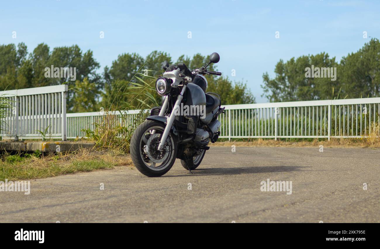 moto parcheggiata sulla strada di fronte a un ponte che esce da un angolo Foto Stock