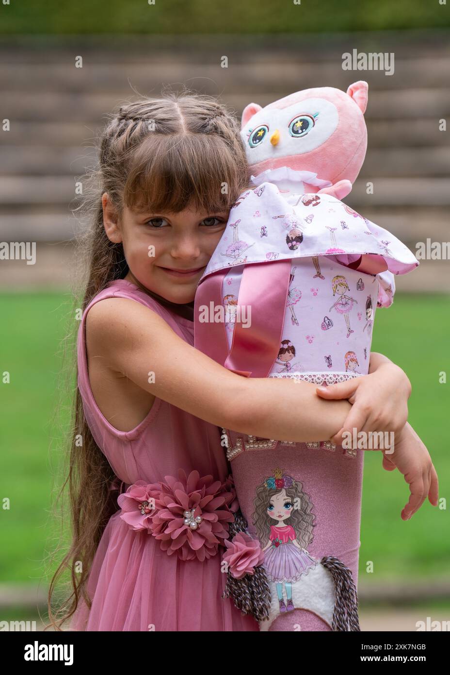 Bambina felice che abbraccia il suo cono scolastico per strada. Foto Stock