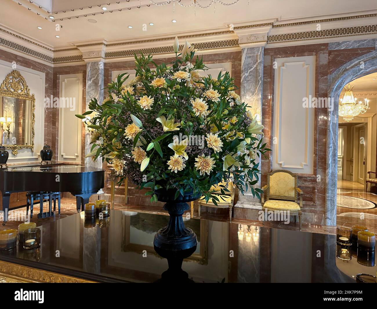 Vaso con bellissimi gigli e dalie sul tavolo a specchio nella hall dell'hotel di lusso Foto Stock