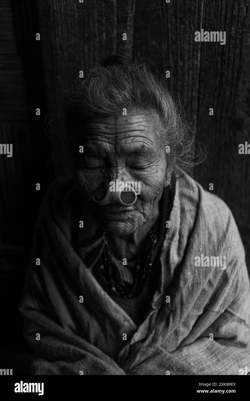 Un'anziana donna Apatani con tatuaggi facciali e tappi per il naso, che simboleggia le tradizioni e la storia profonde della tribù Apatani. Foto Stock