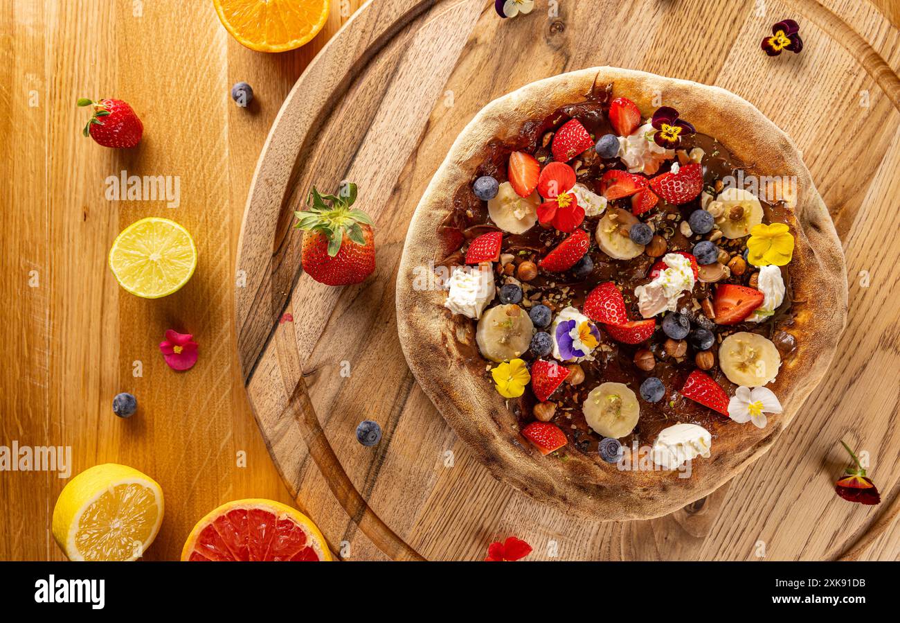 Vista dall'alto di una pizza dolce da dessert condita con frutta fresca e frutti di bosco su un rustico tavolo di legno Foto Stock