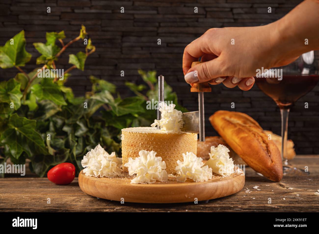 Donna che affetta del delizioso formaggio su un tagliere di legno Foto Stock