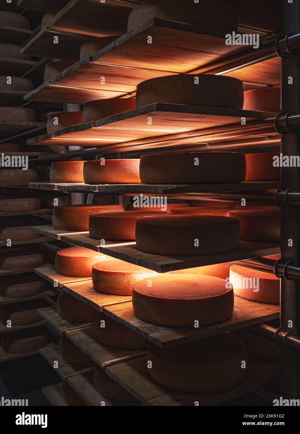 Grandi forme di formaggio stanno maturando su scaffali di legno in una cantina Foto Stock