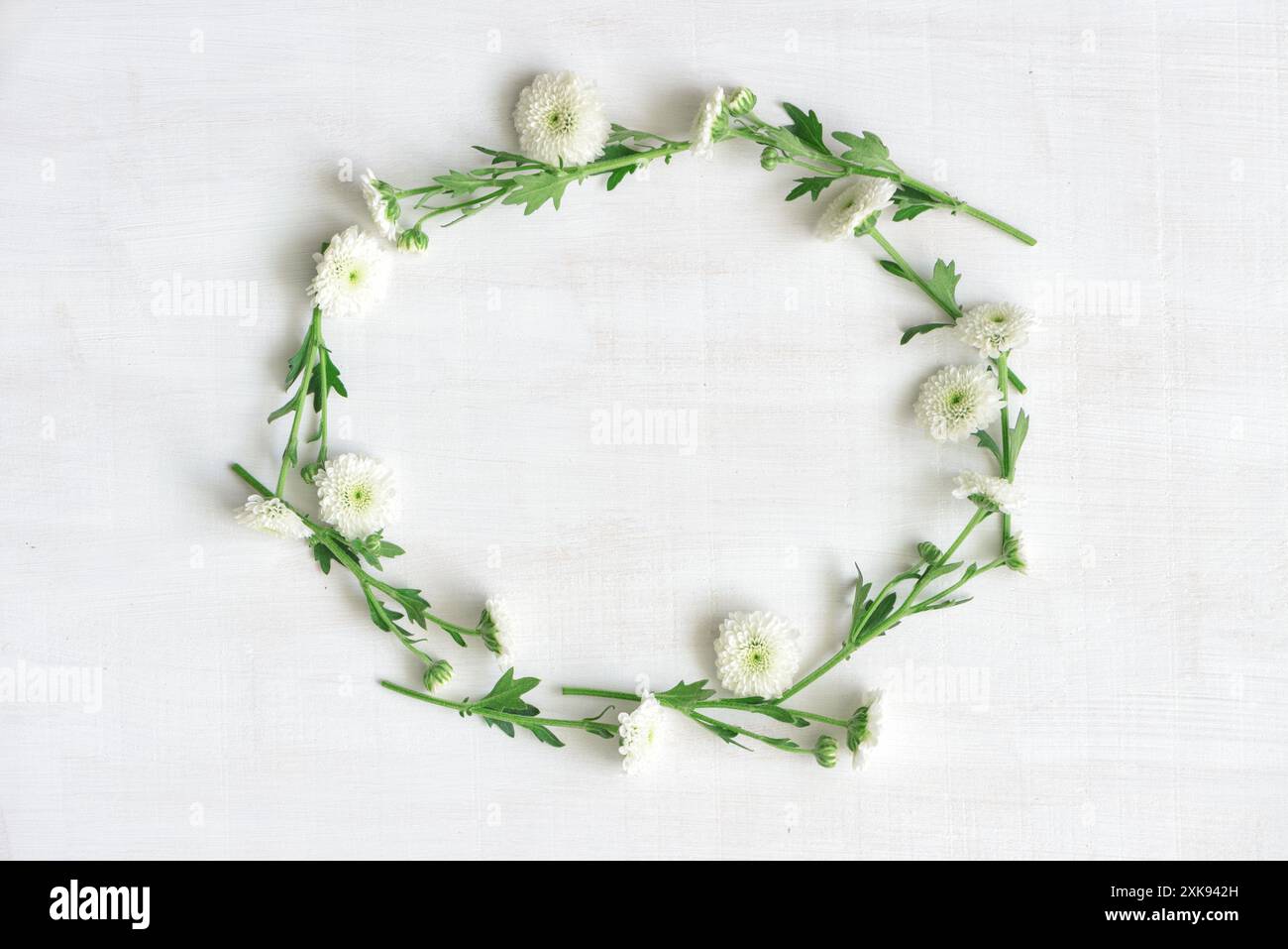 Ghirlanda di fiori bianchi su sfondo di legno bianco Foto Stock