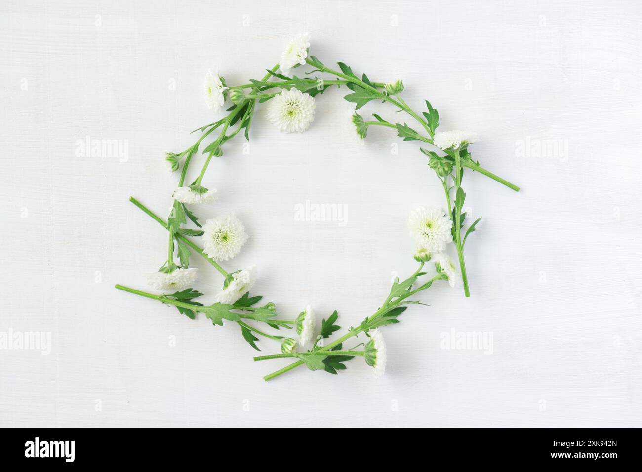 Splendida corona di fiori bianchi su sfondo bianco in legno Foto Stock