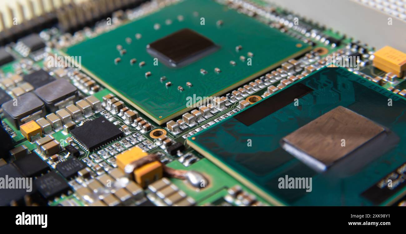 Primo piano dettagliato di una scheda a circuito stampato elettronica che mostra microchip, resistori e altri componenti, che rappresentano la tecnologia e l'hardware moderni. Foto Stock
