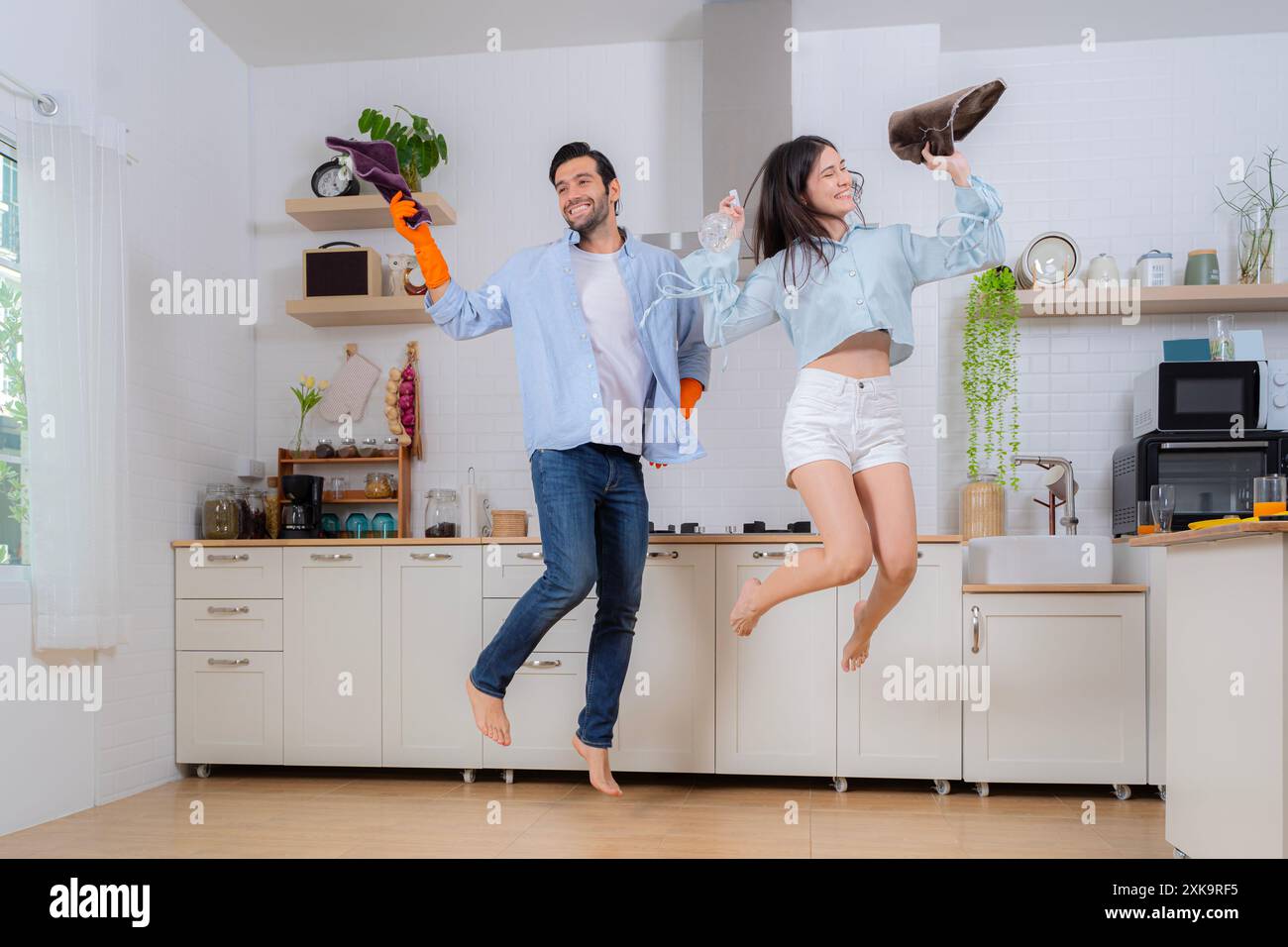 Igiene, lavori domestici nel tempo libero. Giovane coppia di famiglia che fa le pulizie in casa. Concetto di pulizia. Allegro giovane donna europea e uomo lavano Foto Stock