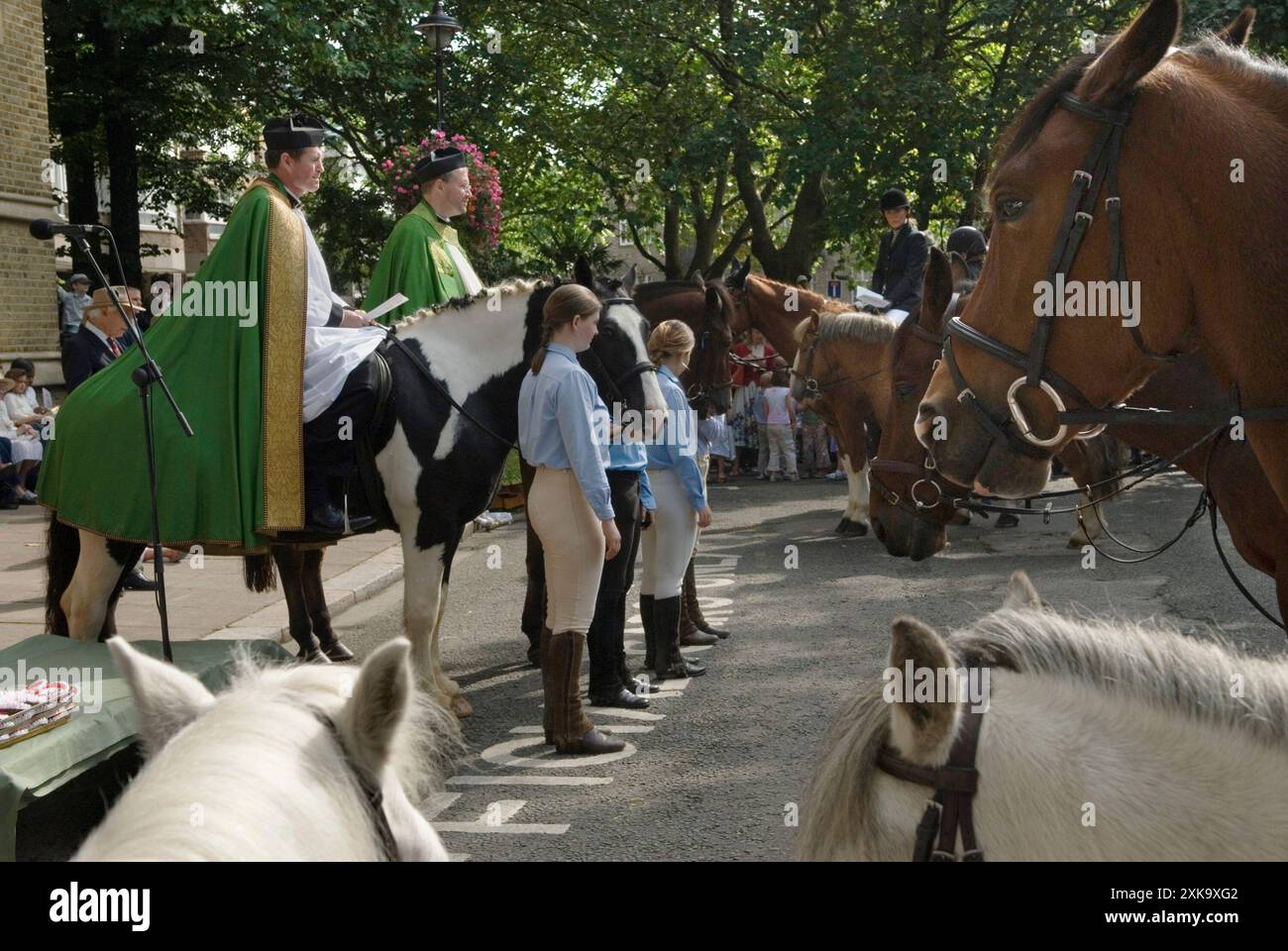 Domenica dei Cavalieri, Londra. Il vicario della chiesa di San Giovanni di Hyde Park, appare davanti alla sua congregazione su un cavallo una tradizione di San Giovanni nota come la domenica del Cavaliere. I cavalli si radunano sul piazzale della chiesa per una benedizione, seguito da un giro e una presentazione di rosoni. Ragazze delle scuderie di cavalli locali e membri del London Pony Club. Il Rev Stephen Mason (R) insieme a e Revd Christopher Burke (L) il Rettore della Chiesa Stepeny. Inghilterra anni '2006 2000 Regno Unito HOMER SYKES Foto Stock