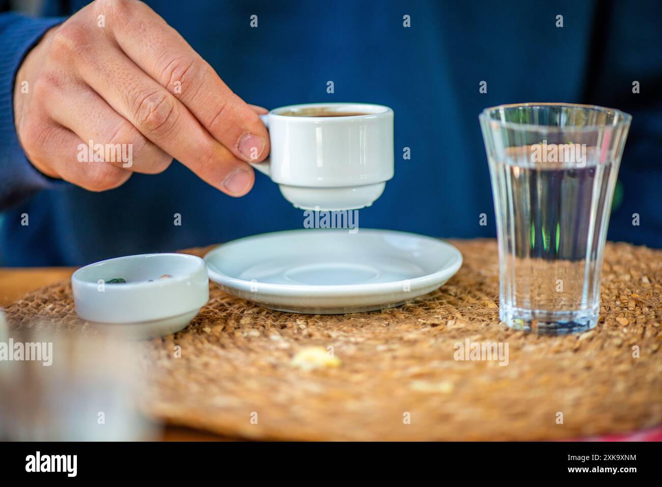 Una foto che cattura un uomo che gusta un tradizionale caffè turco con un bicchiere d'acqua e cioccolato di ciottoli, mostrando una deliziosa presentazione culturale. Foto Stock