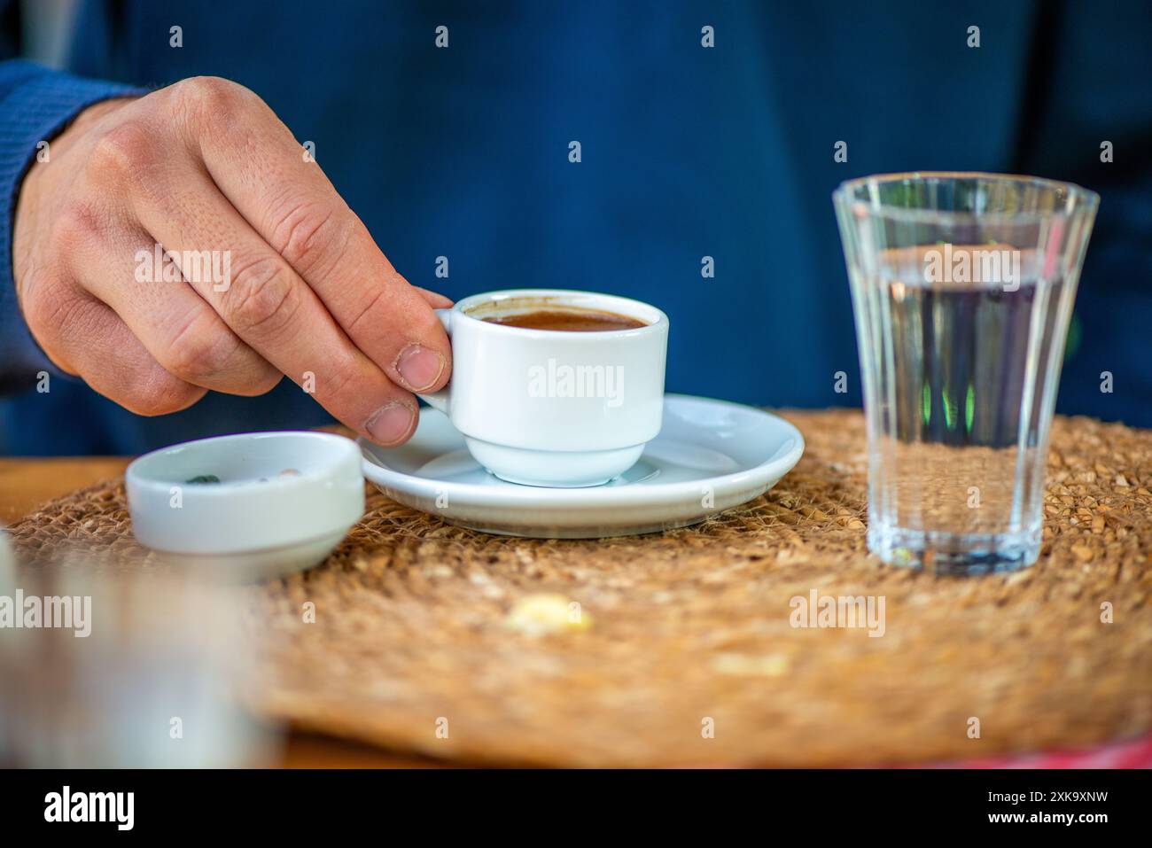 Una foto che cattura un uomo che gusta un tradizionale caffè turco con un bicchiere d'acqua e cioccolato di ciottoli, mostrando una deliziosa presentazione culturale. Foto Stock