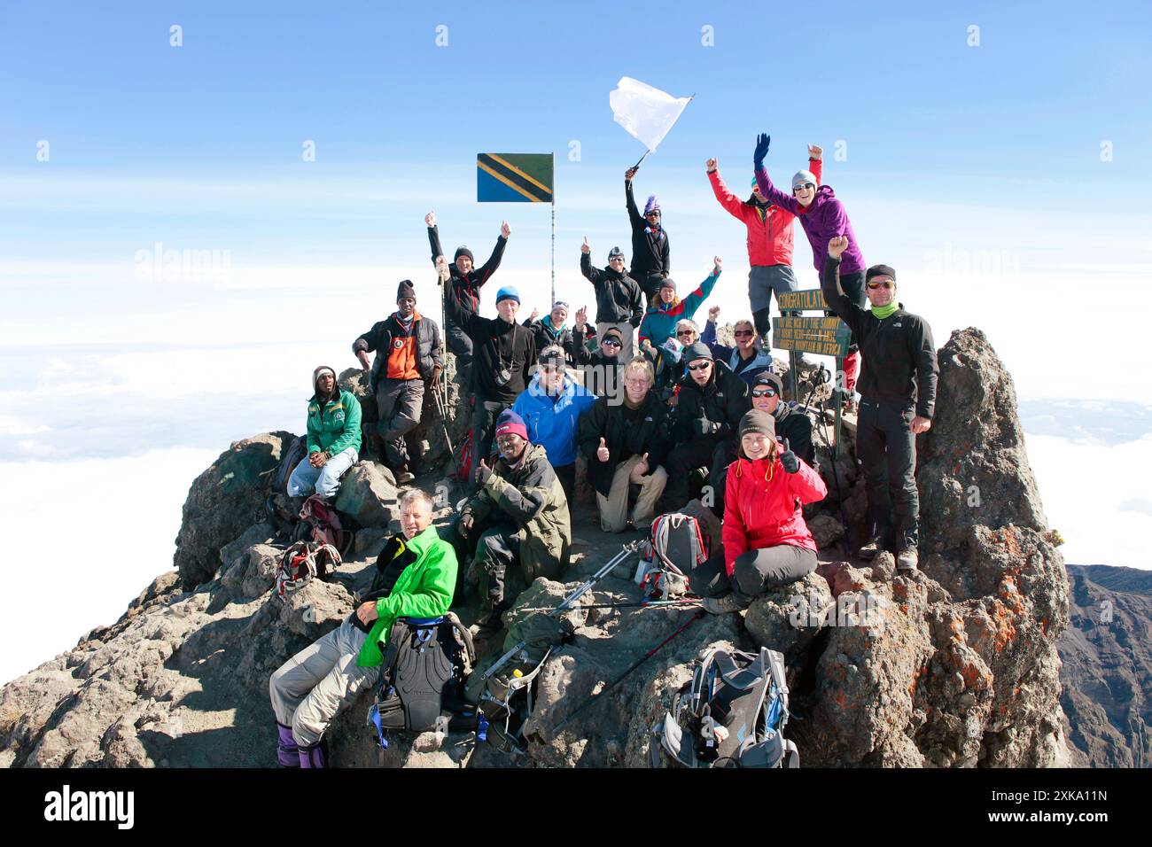 Un gruppo di escursionisti è felice e festeggia sulla cima del Monte Meru, una montagna di trekking in Africa, vicino al Kilimanjaro. Foto Stock