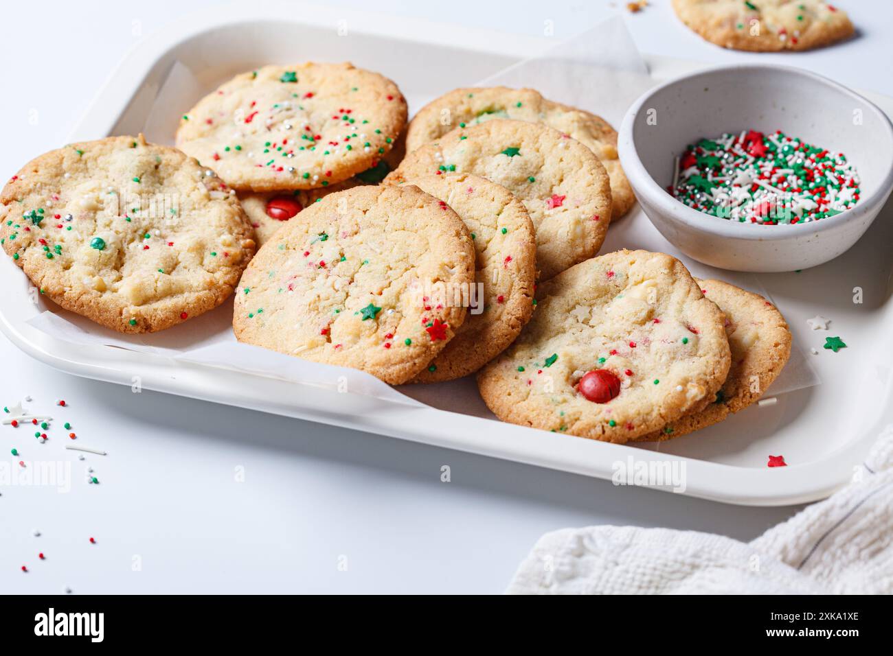 Biscotti di Natale con cioccolato bianco e sprinkles verde-rosso, sfondo bianco. Concetto di dessert natalizi. Foto Stock