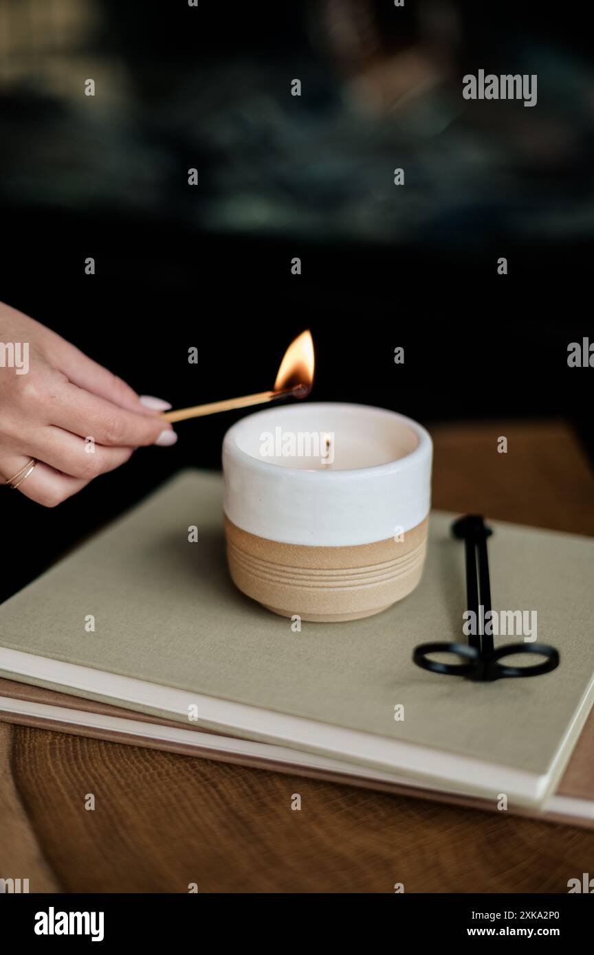 Illuminare a mano una candela sopra i libri impilati. Foto Stock