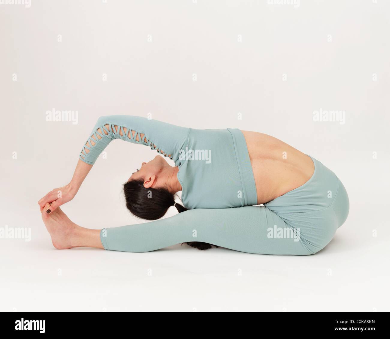 Giovane donna che pratica l'asana su uno studio di sfondo bianco. Foto Stock