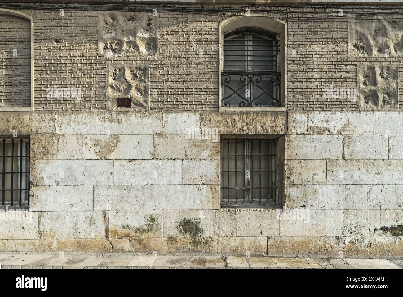 Le facciate in pietra con finestre barrate sono elementi architettonici che danno un aspetto rustico e tradizionale agli edifici Foto Stock