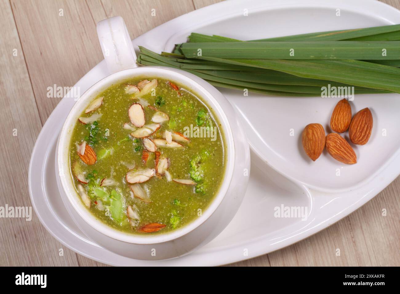 Una ciotola di zuppa di broccoli con mandorle a fette e verdure fresche Foto Stock