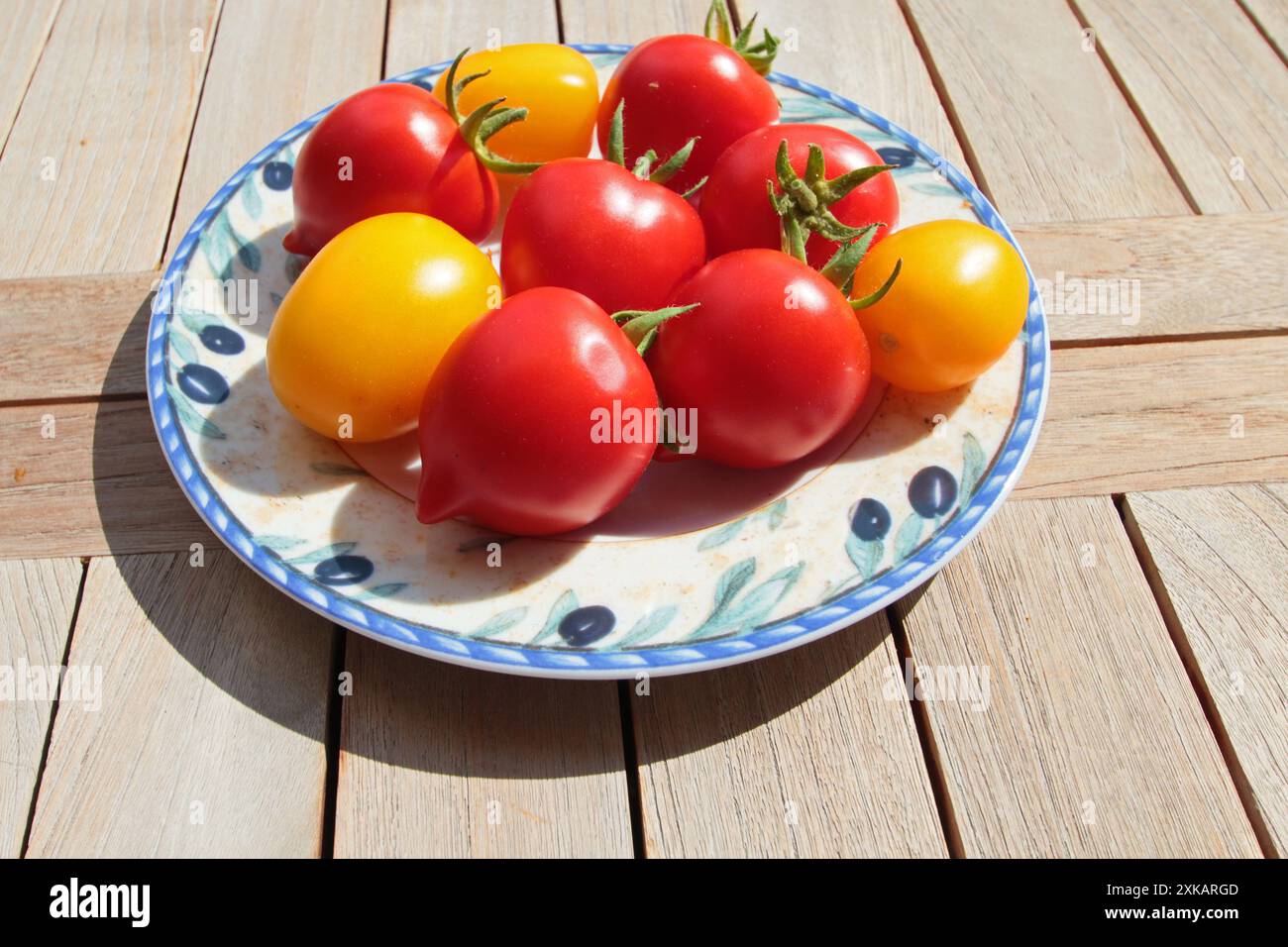 i pomodori rossi e gialli del giardino giacciono su un piatto su un tavolo di legno Foto Stock