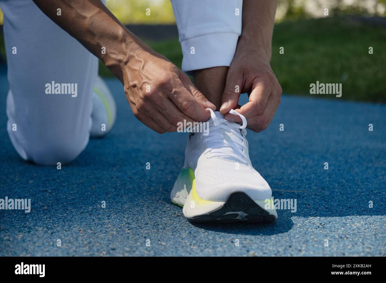 Atleta che prepara l'allenamento. Ultima preparazione prima dell'analisi. Uomo atleta che lega scarpe da running prima di allenarsi. Scarpe da running da vicino. Foto Stock