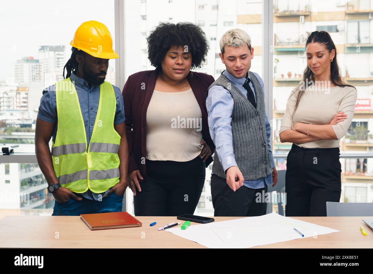 Gruppo di persone in affari che discutono dei piani di costruzione che sono sul tavolo, sono riunite per prendere decisioni, analizzare e pensare a un nuovo progetto Foto Stock