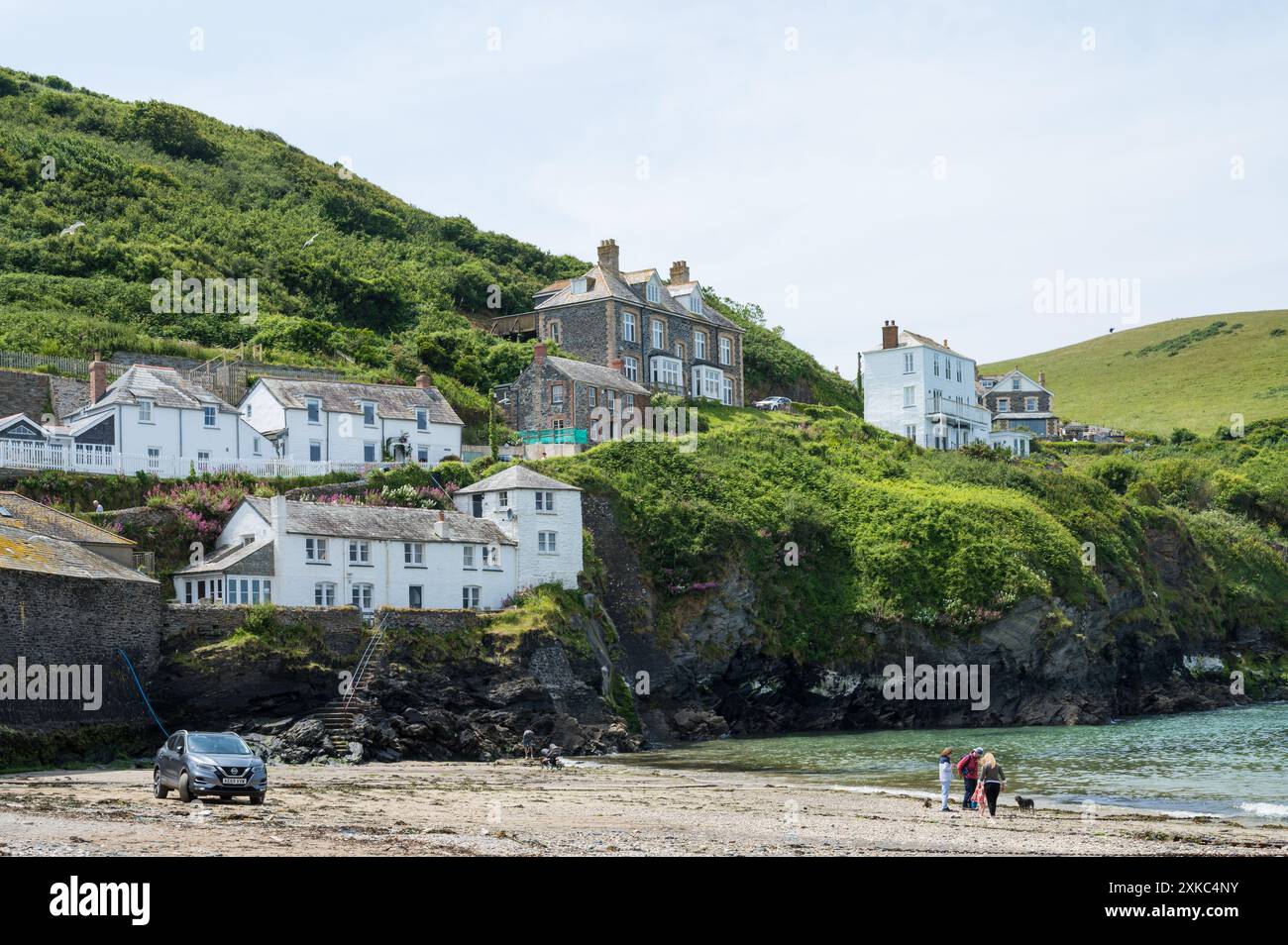 Persone che si godono una giornata estiva soleggiata sulla spiaggia del porto di Port Isaac, Cornovaglia, Inghilterra, Regno Unito Foto Stock