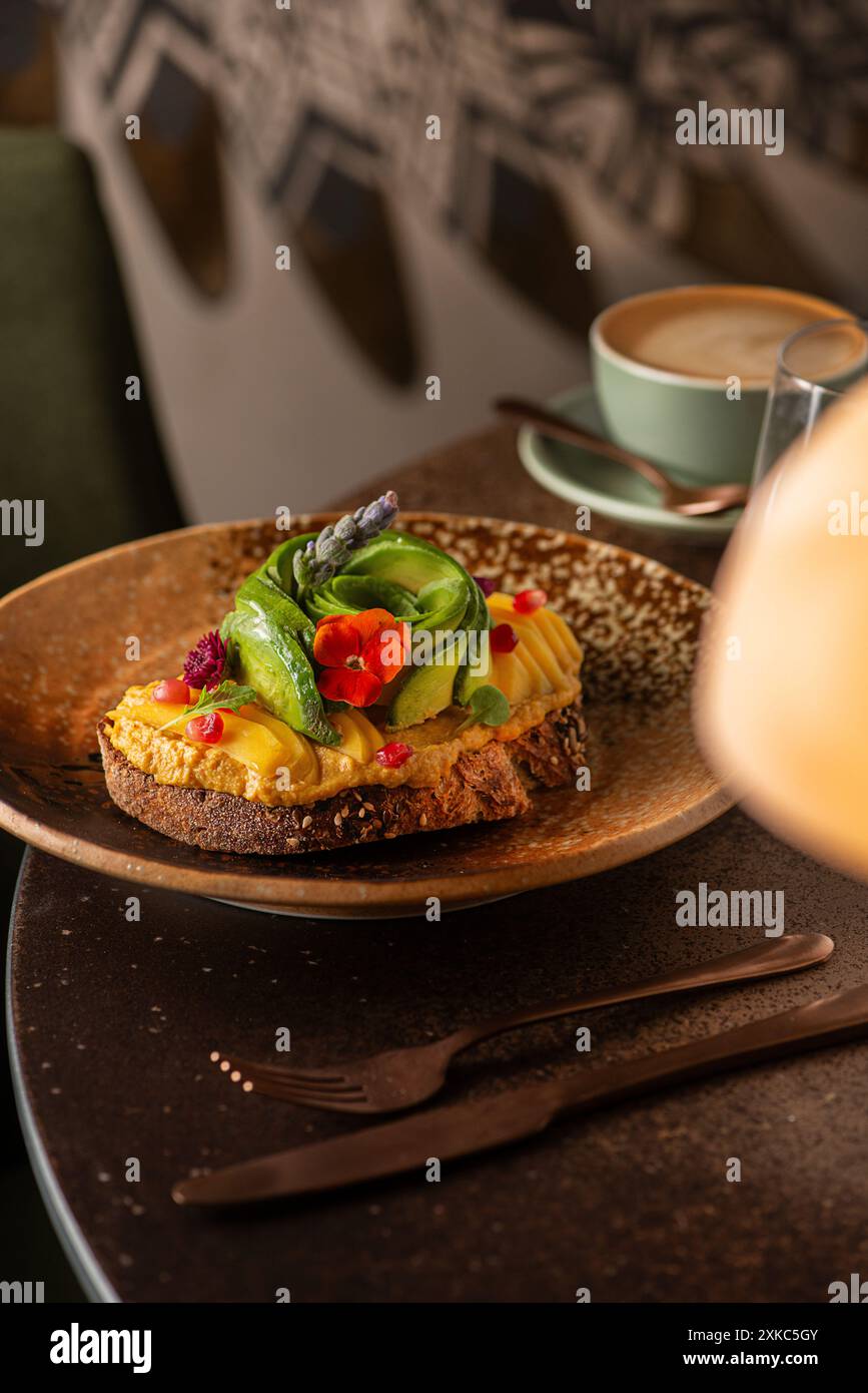 Brindisi all'avocado e all'hummus su un tavolo del ristorante. Ora del brunch. Pane a lievitazione naturale. Foto Stock