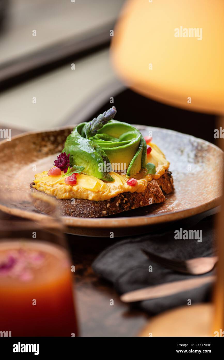 Brindisi all'avocado e all'hummus su un tavolo del ristorante. Ora del brunch. Pane a lievitazione naturale. Foto Stock