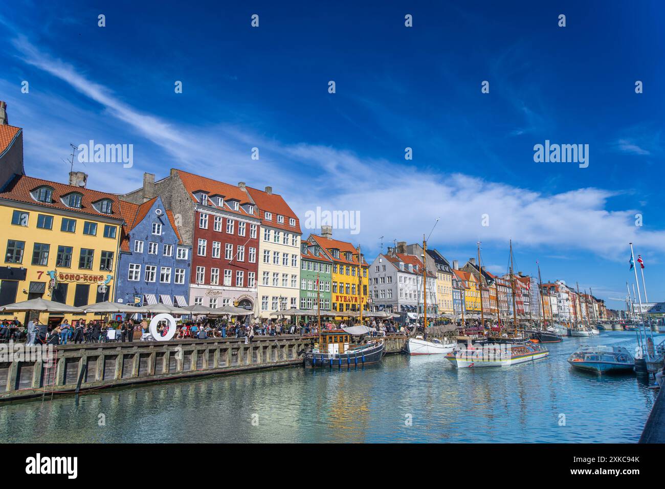 Copenaghen, Danimarca - 29 aprile 2024: Vivace lungomare di Nyhavn fiancheggiato da case e canali colorati del XVII secolo. Foto Stock