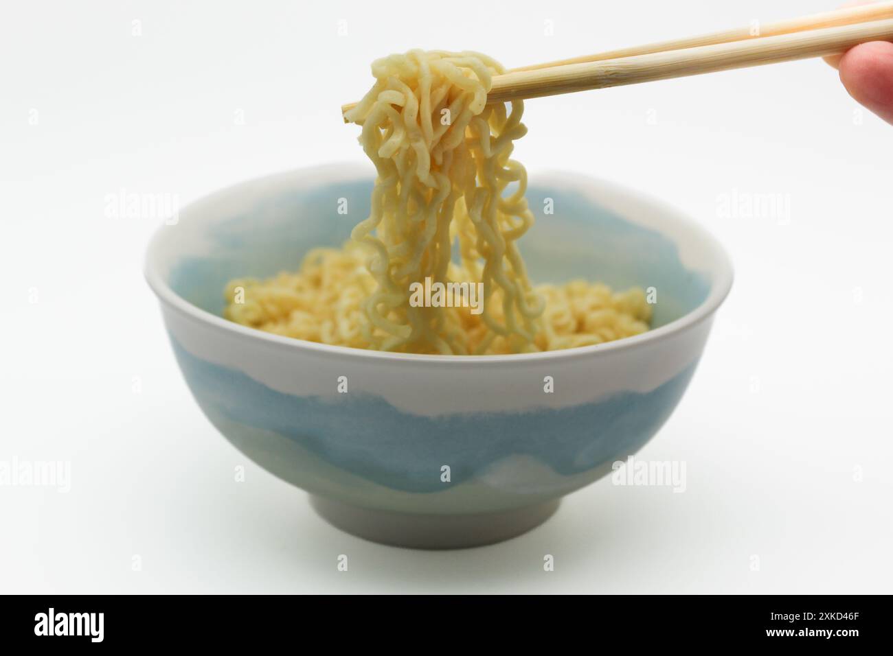Spaghetti istantanei nel recipiente con bacchette su sfondo bianco Foto Stock