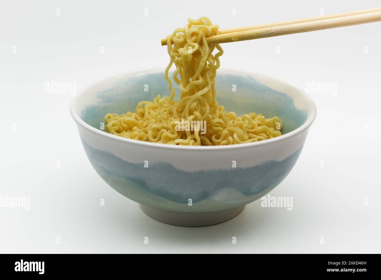 Spaghetti istantanei nel recipiente con bacchette su sfondo bianco Foto Stock